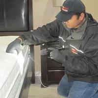 Bed bug inspection technician checking a mattress and bed frame for signs of infestation in Colorado Springs, CO